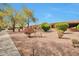 Well-maintained exterior with desert landscaping, mature trees, and a covered patio area at 16131 W Indianola Ave, Goodyear, AZ 85395