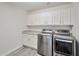 Well-equipped laundry room with modern washer, dryer, granite counters, and white cabinets at 16131 W Indianola Ave, Goodyear, AZ 85395
