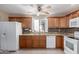Kitchen featuring brown cabinets, granite countertops, white appliances, and tiled backsplash at 16616 E Palisades Blvd # 109, Fountain Hills, AZ 85268