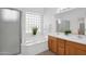 Bright bathroom showcasing a soaking tub with glass block window and double sink vanity at 17443 N Goldwater Dr, Surprise, AZ 85374