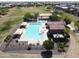 Aerial view highlighting a refreshing community pool with lounge chairs, splash pad and shade umbrellas at 19072 N Ventana Ln, Maricopa, AZ 85138
