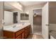 Double sink bathroom vanity with warm toned walls and bedroom access at 19072 N Ventana Ln, Maricopa, AZ 85138
