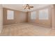 Neutral toned main bedroom with plush carpet, three windows, and a ceiling fan at 19072 N Ventana Ln, Maricopa, AZ 85138
