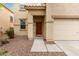 Inviting front entrance with a solid wood door, desert landscaping, and a two-car garage at 19072 N Ventana Ln, Maricopa, AZ 85138