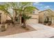 Two story tan home featuring desert landscaping, a two-car garage, and a lovely mature tree at 19072 N Ventana Ln, Maricopa, AZ 85138