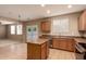 Well-lit kitchen with an island, wooden cabinetry, and a door to the backyard at 19072 N Ventana Ln, Maricopa, AZ 85138