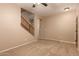 Spacious living room with neutral carpet, a ceiling fan, and access to the stairway at 19072 N Ventana Ln, Maricopa, AZ 85138
