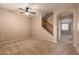 Spacious living room with neutral carpet, a ceiling fan, and access to the stairway at 19072 N Ventana Ln, Maricopa, AZ 85138