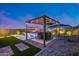 Large, landscaped backyard featuring a pool, outdoor kitchen, dining area, and a cozy lounge area with a pergola at 19443 W Valle Vista Way, Litchfield Park, AZ 85340