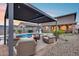 Outdoor covered seating area with plush chairs is adjacent to the sparkling in ground pool and fire pit at 19443 W Valle Vista Way, Litchfield Park, AZ 85340