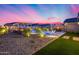 Lush backyard with a pool, two pergolas with fire pits, an outdoor kitchen with bar top seating, and tropical plants at 19443 W Valle Vista Way, Litchfield Park, AZ 85340
