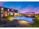 Amazing landscaped backyard featuring a shimmering pool, a cozy fire pit lounge area, a kitchen and a bar top at 19443 W Valle Vista Way, Litchfield Park, AZ 85340