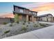 Two-story home featuring stone-clad porch columns, desert landscaping, a concrete driveway, and privacy fencing at 19443 W Valle Vista Way, Litchfield Park, AZ 85340