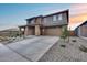 Two-story home featuring stone-clad porch columns, desert landscaping, and a concrete driveway to the two-car garage at 19443 W Valle Vista Way, Litchfield Park, AZ 85340