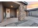 Covered front porch with stone columns, 'Welcome' decor, and two carriage lights, leading to the two-car garage at 19443 W Valle Vista Way, Litchfield Park, AZ 85340