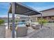Outdoor covered seating area with plush chairs is adjacent to the sparkling in ground pool and fire pit at 19443 W Valle Vista Way, Litchfield Park, AZ 85340