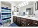 Bright bathroom with dual sinks, dark wood cabinetry, and a blue striped shower curtain for a serene design at 19622 N 66Th Ln, Glendale, AZ 85308