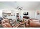 Spacious living room featuring leather furniture and TV, with a view into an open-concept kitchen at 19622 N 66Th Ln, Glendale, AZ 85308