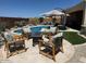 Cozy backyard featuring a pool, comfortable seating area with umbrella, and lush faux grass at 26904 W Kerry Ln, Buckeye, AZ 85396
