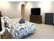 Bedroom with a dark wood dresser and a large TV. Large bed with beautiful patterns at 26904 W Kerry Ln, Buckeye, AZ 85396