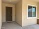 Covered front entry with a solid door and a sidelight, showcasing neutral stucco walls at 26904 W Kerry Ln, Buckeye, AZ 85396