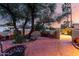 Enchanting brick patio with lush greenery, mature trees, and an inviting fire pit create a serene outdoor space at 3258 E Vogel Ave, Phoenix, AZ 85028