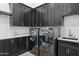 Modern laundry room with dark cabinets, sink, and front-load washer and dryer at 3939 W Fox Rd, Laveen, AZ 85339