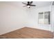 Bright bedroom featuring wood floors, a ceiling fan, and shutters on the window at 5607 N 76Th Pl, Scottsdale, AZ 85250