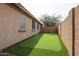 Backyard featuring artificial turf, ideal for recreation and relaxing, with a privacy wall and mature tree at 6796 W Evergreen Ter, Peoria, AZ 85383