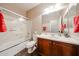 Bathroom with tile floor, wood vanity, framed mirror, and tiled shower and tub at 6796 W Evergreen Ter, Peoria, AZ 85383