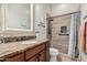 Bathroom featuring decorative mirror, granite vanity, and tiled walk-in shower at 7589 W Firebird Dr, Glendale, AZ 85308