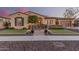 Charming single-story home with a beautifully landscaped front yard, decorative wrought iron gate, and a welcoming walkway at 7589 W Firebird Dr, Glendale, AZ 85308