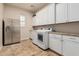Bright laundry room features stainless steel refrigerator and modern white washer and dryer at 7589 W Firebird Dr, Glendale, AZ 85308