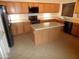 Spacious kitchen features wooden cabinets, black appliances, and a central island for meal preparation and storage at 10302 E Cicero Cir, Mesa, AZ 85207