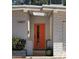 Close up of the entrance to the home with a bright orange front door, white brick and green potted plant at 12807 N 21St Dr, Phoenix, AZ 85029