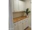 Well-lit mudroom boasts butcher block counters and white cabinets with gold hardware at 12807 N 21St Dr, Phoenix, AZ 85029