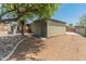 Backyard featuring gravel landscaping, mature trees, an enclosed storage building, and covered patio at 15602 N 56Th Pl, Scottsdale, AZ 85254