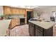 Kitchen featuring wooden cabinetry, a functional island, black appliances, and terracotta tile flooring at 15602 N 56Th Pl, Scottsdale, AZ 85254