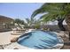 Scenic pool view featuring a rock waterfall, complemented by lush landscaping and comfortable lounge chairs at 16706 N 109Th Way, Scottsdale, AZ 85255