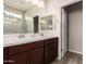 Bathroom with double sinks, a large mirror, and wood cabinets at 17308 W Daley Ln, Surprise, AZ 85387