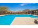 Sparkling community pool with clear blue water, a tanning deck, and well-maintained landscaping for summer enjoyment at 17308 W Daley Ln, Surprise, AZ 85387