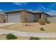 Single story home featuring a two-car garage, desert landscaping and covered front porch at 17308 W Daley Ln, Surprise, AZ 85387