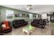 Spacious living room with dark leather couches, a ceiling fan, and a ' table and chairs at 17308 W Daley Ln, Surprise, AZ 85387