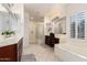 Bright bathroom with tiled floors, dual sinks, glass block shower, vanity, and soaking tub at 19137 W Pasadena Ave, Litchfield Park, AZ 85340