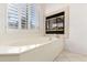 Soaking tub with jets, tile surround, and window view; features an inset fireplace at 19137 W Pasadena Ave, Litchfield Park, AZ 85340