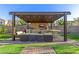 Close-up shot of a BBQ island under a pergola, equipped with seating, countertop, grill, and a TV at 19675 E Oriole Way, Queen Creek, AZ 85142