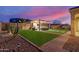 Tranquil backyard showcases an outdoor kitchen, vibrant artificial grass, and desert landscaping at 19675 E Oriole Way, Queen Creek, AZ 85142