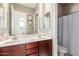 Well-lit bathroom boasts double sinks with cherry cabinets, and a separated shower with a curtain at 19675 E Oriole Way, Queen Creek, AZ 85142