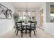 Bright dining area features a round table, black chairs, and stylish chandelier, complemented by natural light from three large windows at 19675 E Oriole Way, Queen Creek, AZ 85142