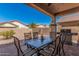 Covered patio with outdoor dining set, barbecue grill, and desert landscaping beyond at 208 W Lantern Way, San Tan Valley, AZ 85143